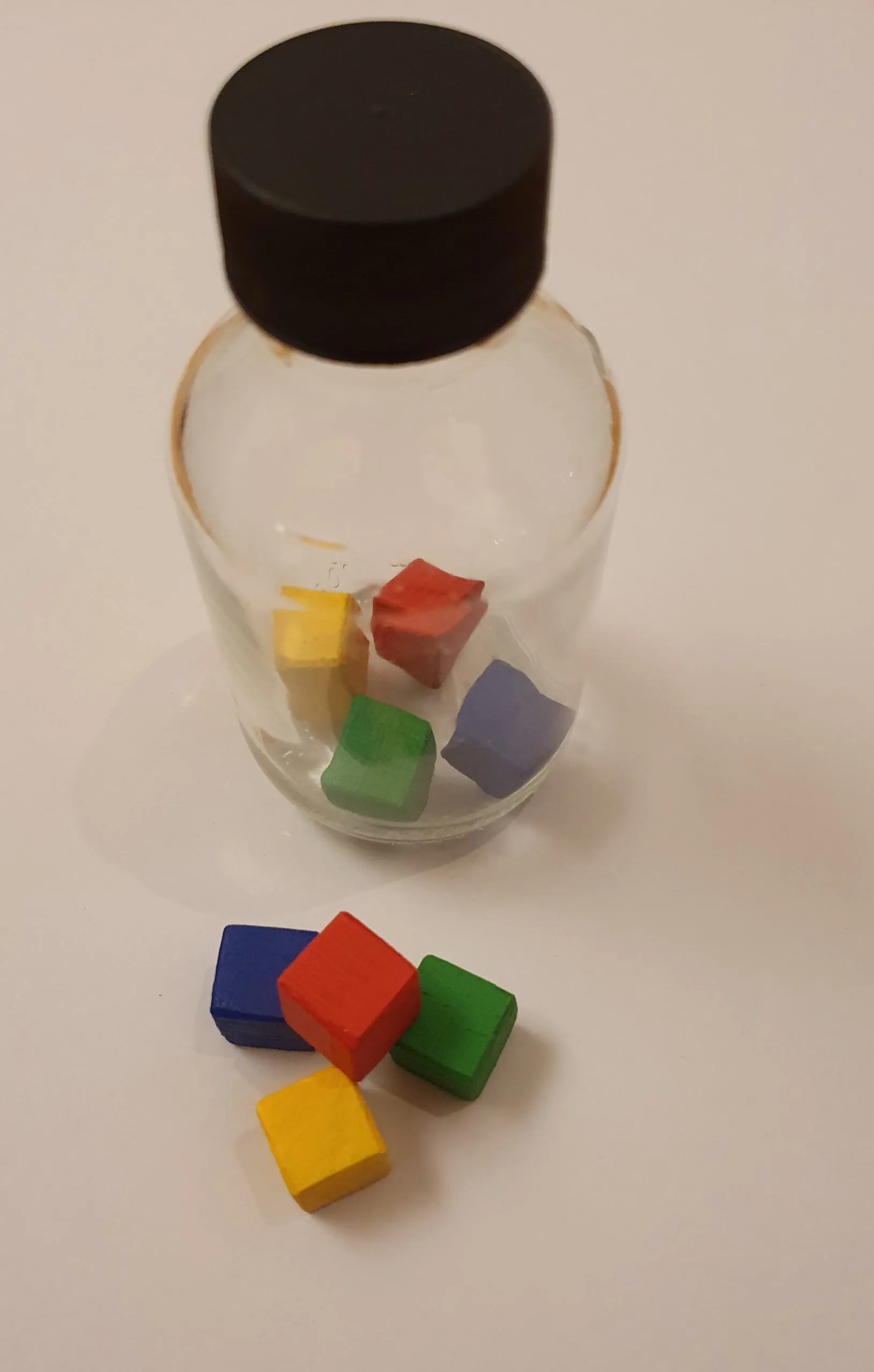 Eingefärbte Holzwürfel in einem Glasfläschchen